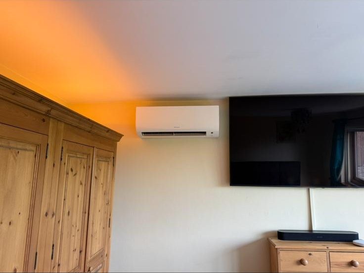 Wall-mounted AC unit installed in a warmly lit bedroom