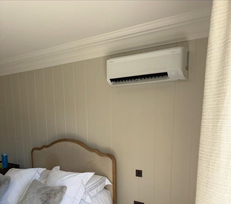 Wall-mounted AC unit installed above a bedroom headboard