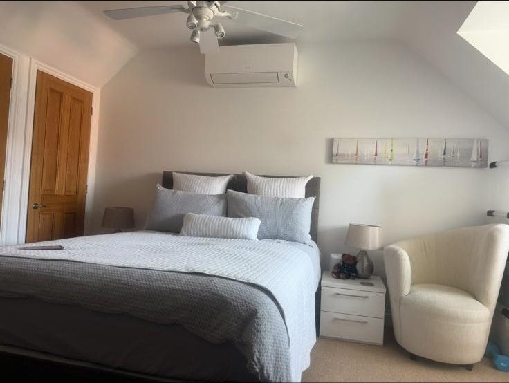 Wall-mounted AC unit installed in a bedroom with sloped ceiling
