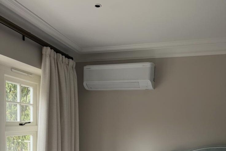 Wall-mounted AC unit installed above a bedroom window