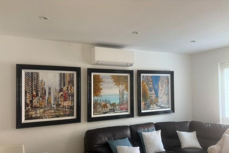 Wall-mounted AC unit installed above a living room sofa