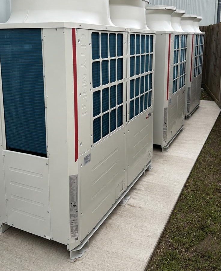 Row of large commercial condenser units outside a warehouse