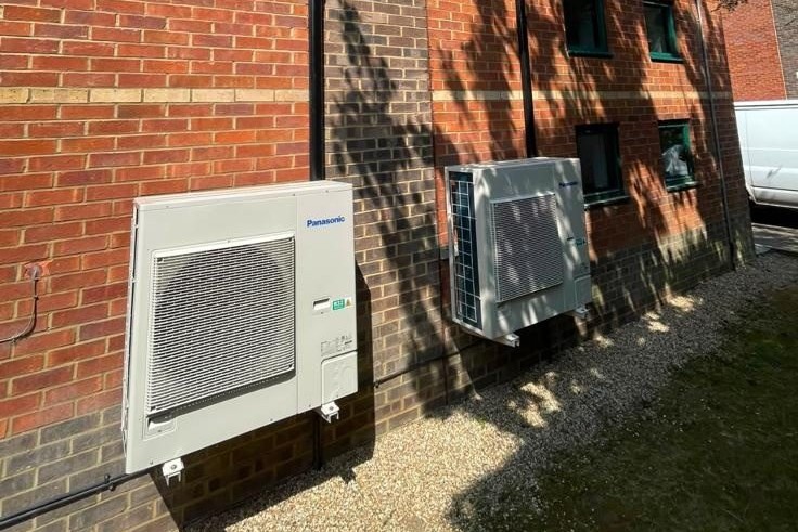 Two outdoor condenser units installed on a multi-storey brick building